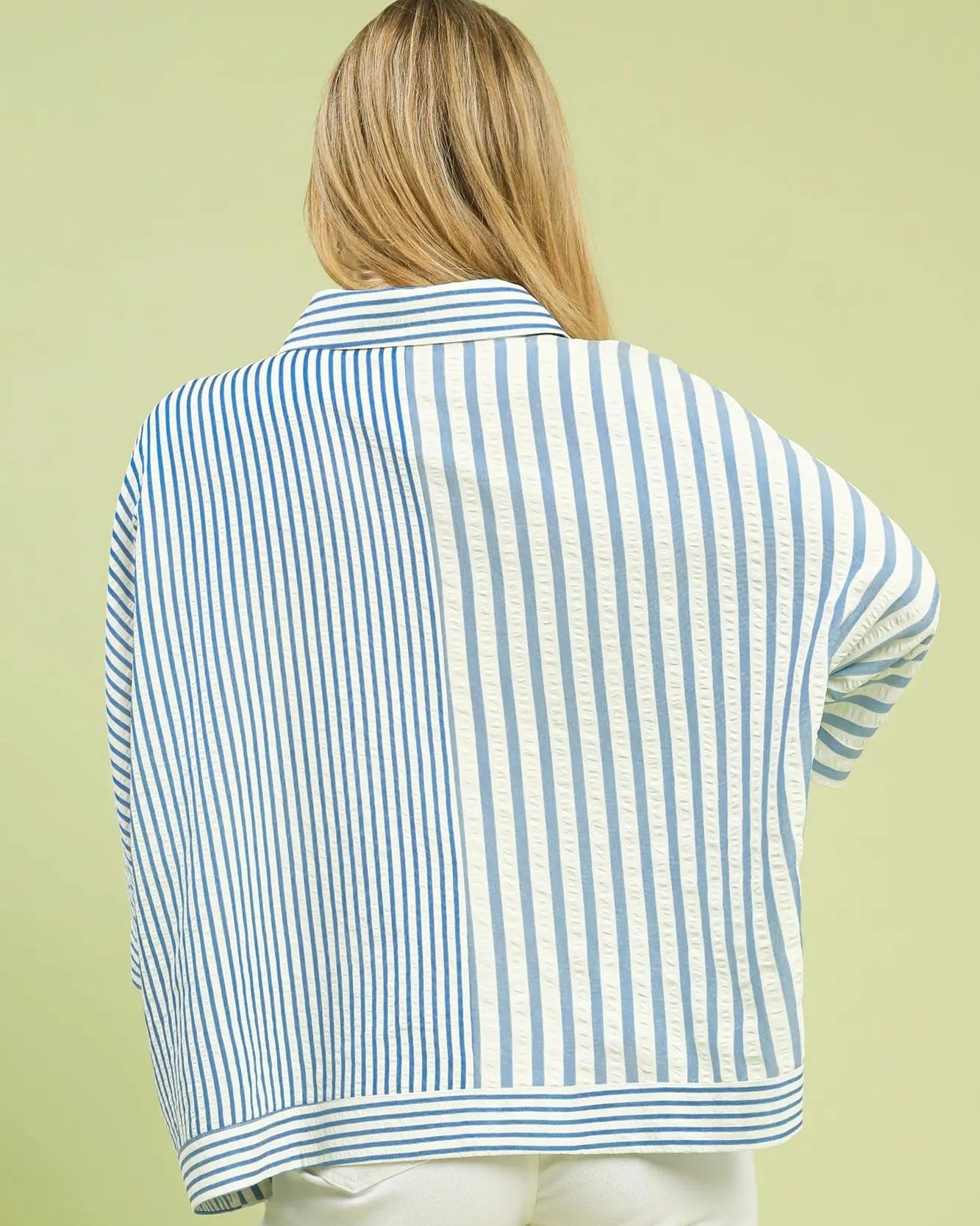 Person wearing a light blue and white striped shirt on a green background