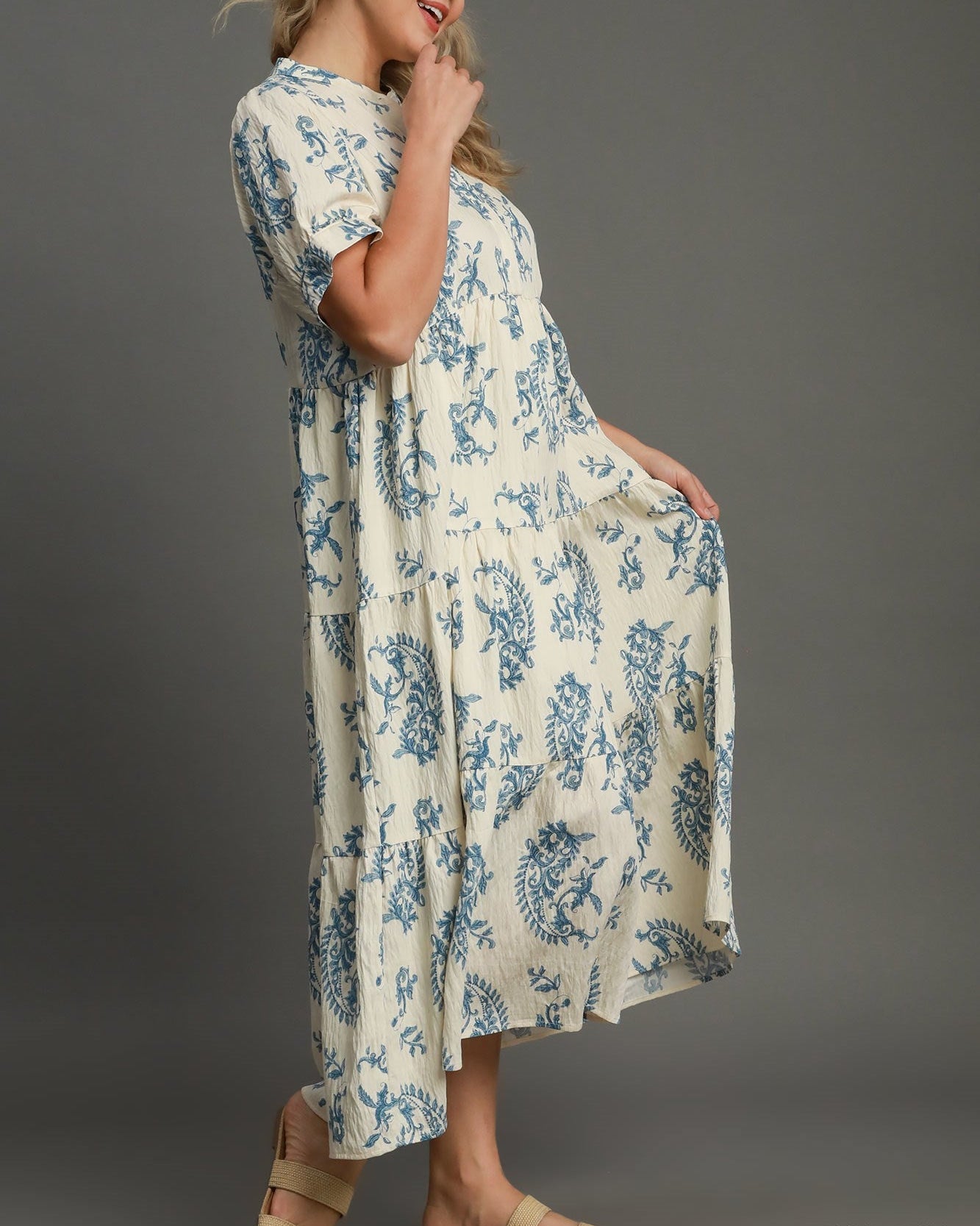 Woman wearing a blue and white floral dress against a gray background