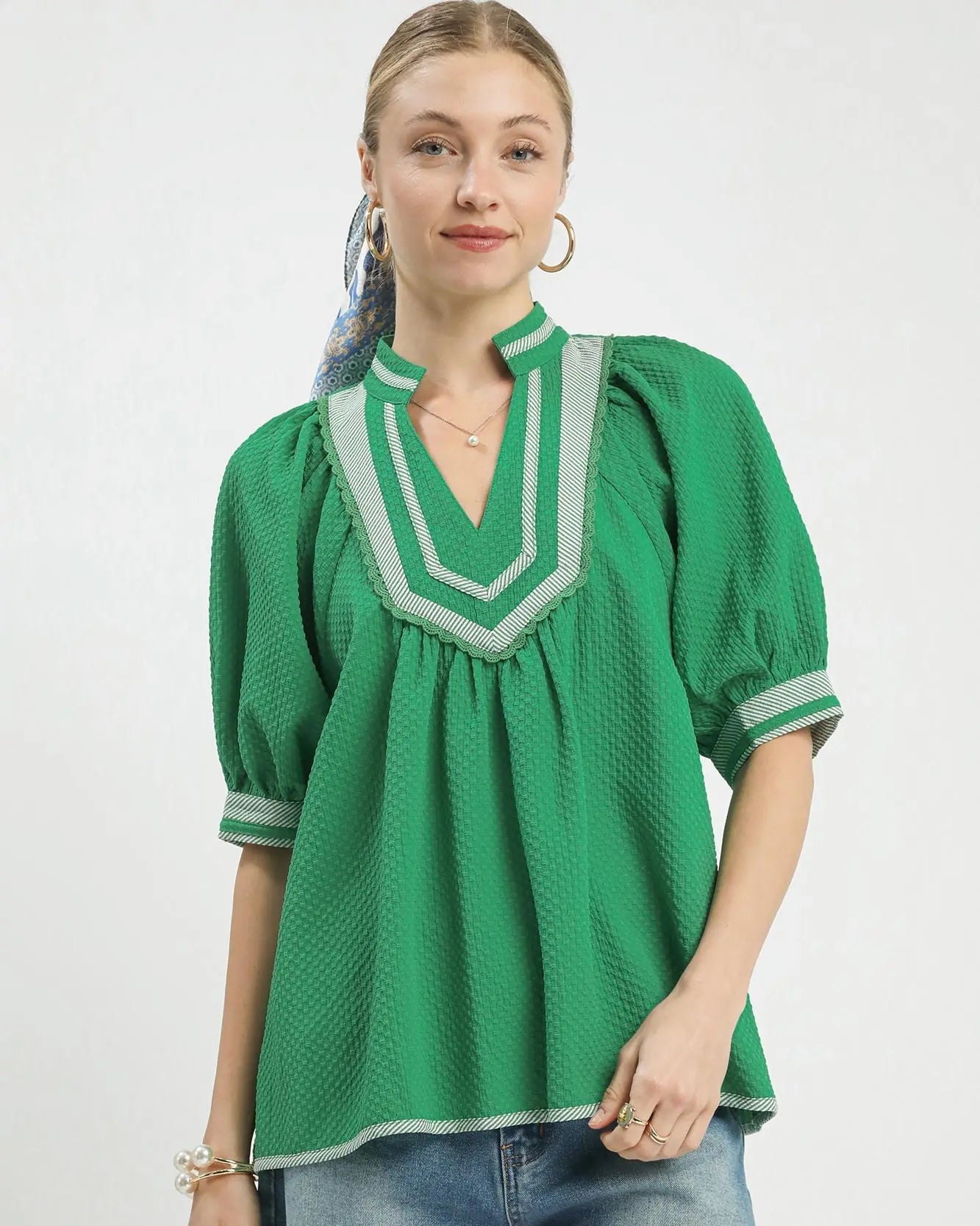 Woman wearing a green blouse with white trim on a white background