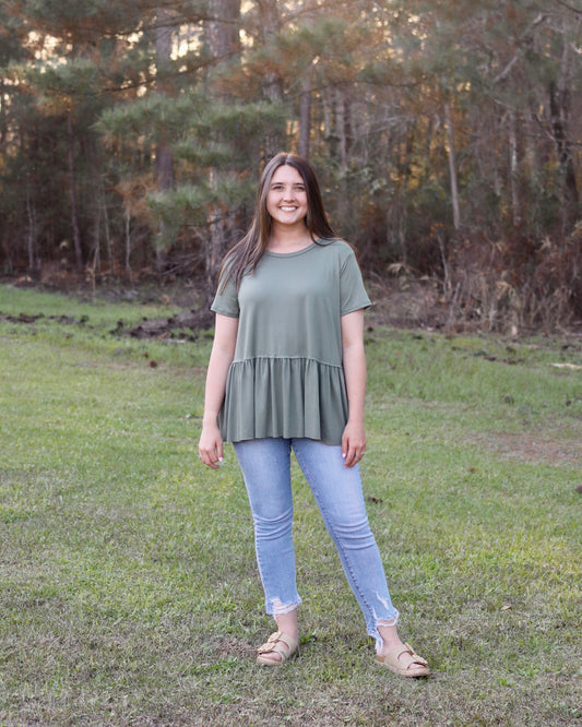 Woman standing in a grassy field with trees in the background