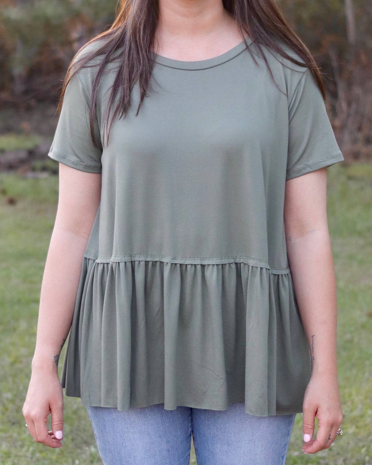 Person wearing a green tiered tunic in an outdoor setting