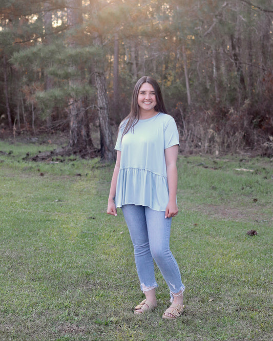 Woman standing in a grassy field with trees in the background