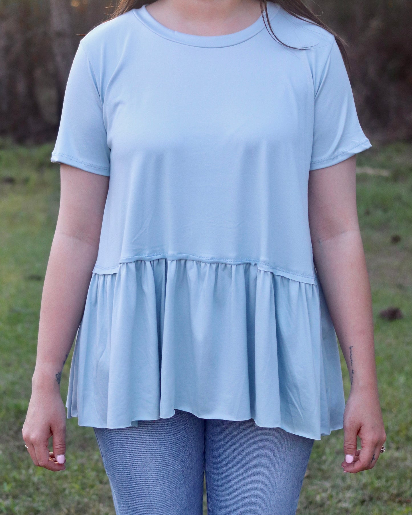 Person wearing a light blue peplum top outdoors