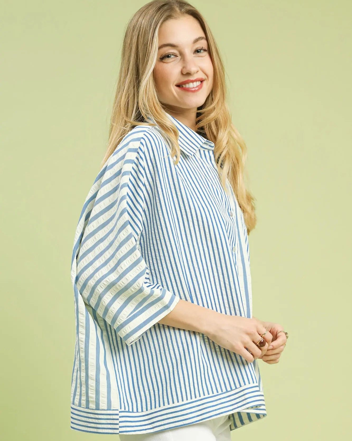 Woman wearing a light blue and white striped shirt against a light green background