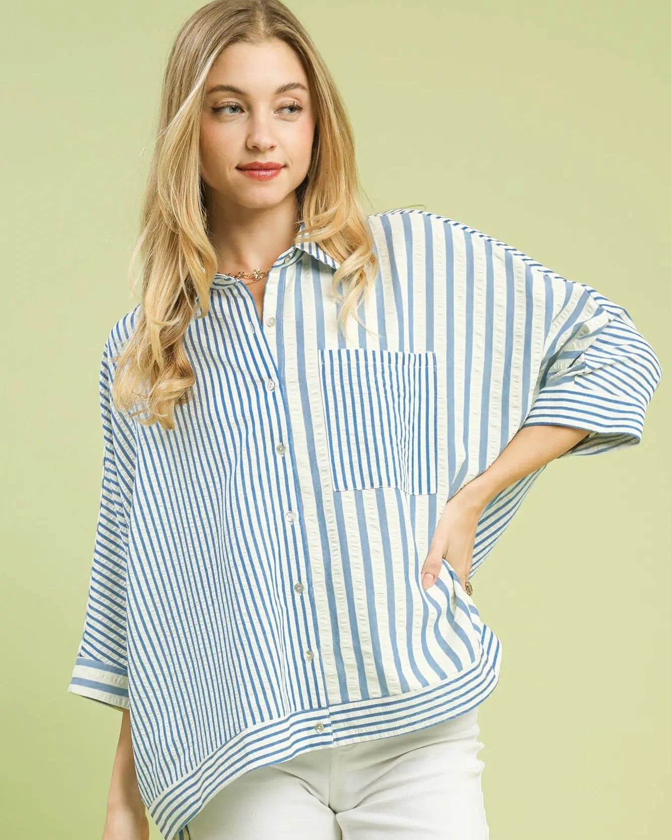 Woman wearing a blue and white striped shirt with a pocket on a light green background