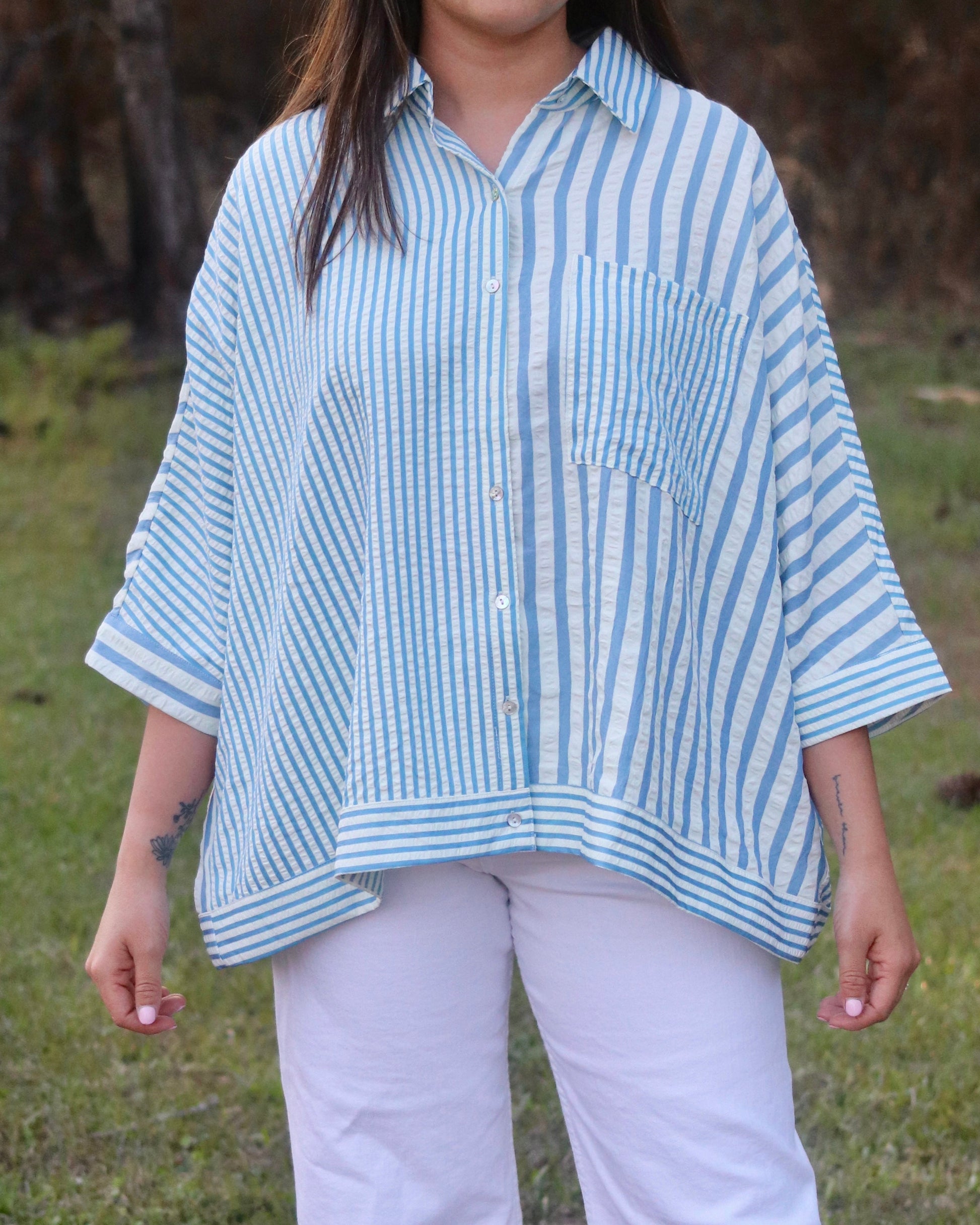 Person wearing a blue and white striped shirt and white pants in an outdoor setting