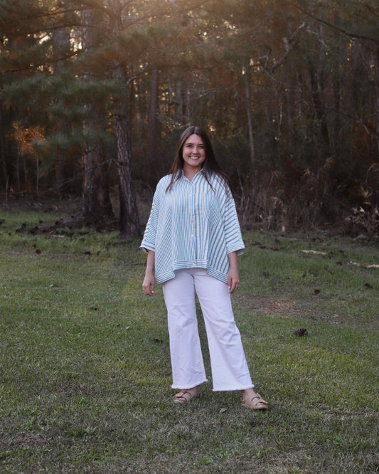 Woman standing in a grassy field with trees in the background